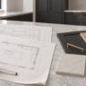 Permit drawings for a home remodel in Virginia, with plan sheets, a tape measure and material samples on a marble kitchen island
